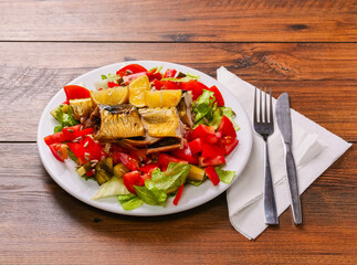 Large plate with fresh lettuce salad, tomato, lemon, sunflower seeds and fine smoked mackerel. Tasty big portion of food served on a wooden table. Healthy diet.