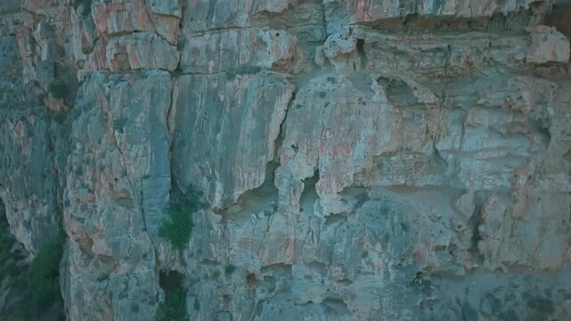 Drone footage of rocky cliffs at Cala del Moraig in Benitatxell, Spain. Detailed close-up of Mediterranean rock textures and natural stone formations.