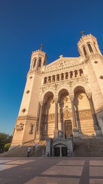 Hyperlapse front view of the Basilica of Notre Dame de Fourviere during sunset in Lyon, France. This iconic minor basilica is illuminated with warm light, overlooking the city from a hilltop timelapse