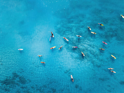 Aerial pic of surfers seating on surfboards and waiting for wave in the middle of ocean with perfect weather and clean water at sunset time in Hawaii paradise, shot on drone from above	
