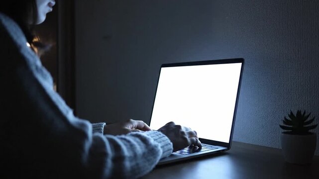 薄暗い部屋でノートパソコンの光に包まれるモダンな夜
