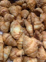 A large, abundant pile of freshly baked, golden brown, and flaky mini croissants.