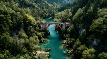 Ancient arched bridge spans vibrant turquoise river flowing through lush dense forested ravine