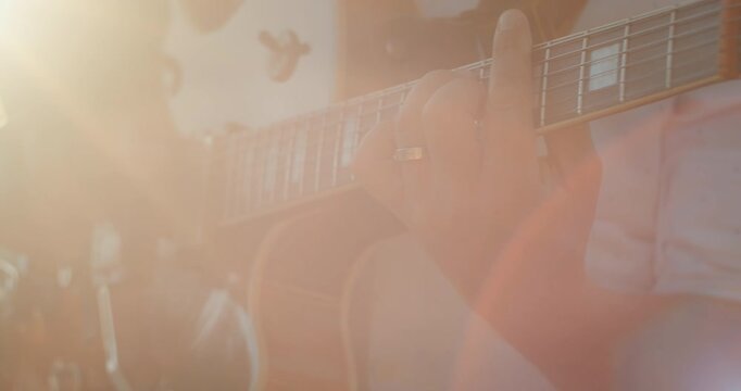 Close-up of man hands playing guitar chords in warm sunlight outdoors
