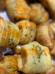 Close-up of golden-brown baked pastries with herbs sprinkled on top, showcasing their flaky texture.