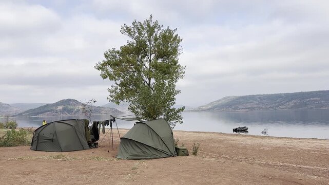 Two carp fishing tents face Lake Salagou with rods set and an inflatable boat ready on shore. Typical scene of carp angling. Check my portfolio for more Salagou footage.