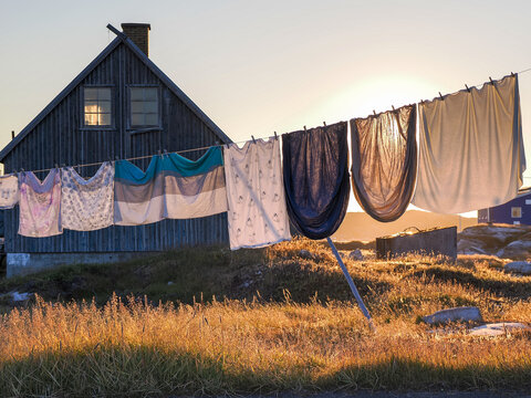 Colorful laundry drying on line in golden light near wooden house in peaceful countryside setting in Greenland