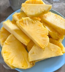 Vibrant, freshly cut pineapple slices on a blue plate, a juicy and naturally sweet tropical delight. Perfect for a refreshing healthy snack or light dessert