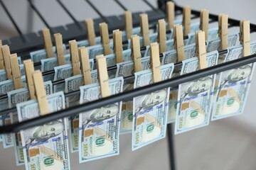 Money laundering. Banknotes hanging on drying rack indoors, closeup