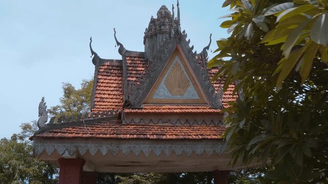 Tiled roof of Wat Svay Romeat Pagoda with traditional chofahs and a gable against the sky. Shot in motion. Shot in motion