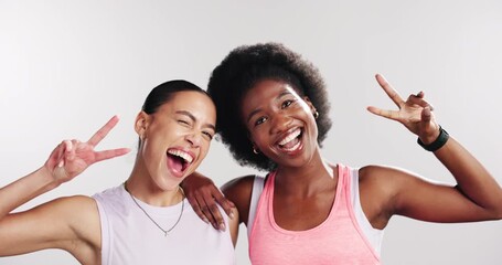Happy woman, fitness and friends with face in studio, hug and peace sign with wink on white background. Girl, excited and embrace in portrait with symbol, emoji and laugh with partner for exercise - Powered by Adobe