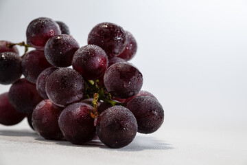 A Bunch of Fresh Red Grapes with Dew Drops on a White Background