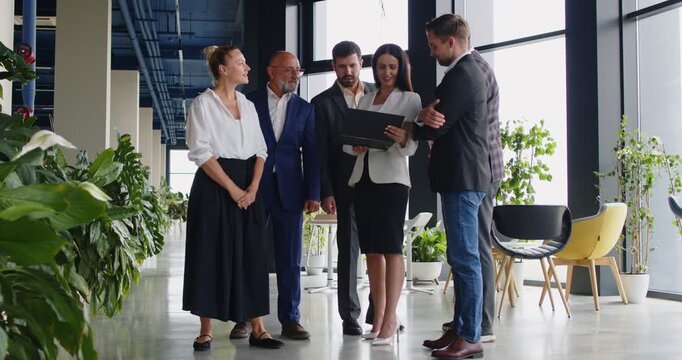 Colleagues meeting for business discussion, document review and team planning in green office. Employees discuss project presentation, partnership strategy, collaboration and metrics analysis