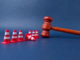 The combination of a gavel and traffic cones can symbolize legal obstacles or the law creating...