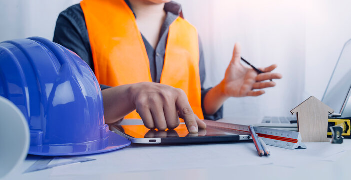 Two colleagues discussing data working and tablet, laptop with on on architectural project at construction site at desk in office