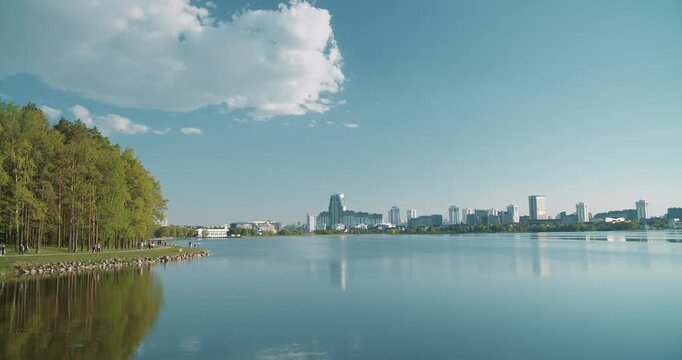 Minsk, Belarus. Reservoir Drozdy. Time Lapse View On Forest, Public Park And City On Background. People Resting Walking At Riverside In Summer Day. City Pond And Park.