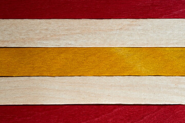 Wooden strips in red, yellow, and light tones arranged in a pattern