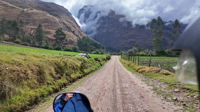Huaraz, Peru: Point of view footage of riding motorcycle on the small road between green field to Laguna Paron showing cloud surrounding mountain in the Cordillera blanca in the Andes