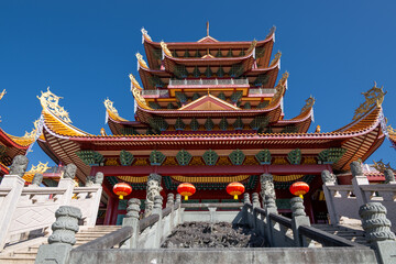 Fototapeta premium Magnificent Traditional Chinese Temple Architecture with Ornate Roofs and Red Lanterns Under a Clear Blue Sky