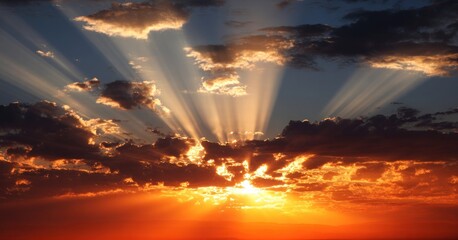 Fototapeta premium Sunlight streaming through clouds at sunset, casting a warm glow over the sky.