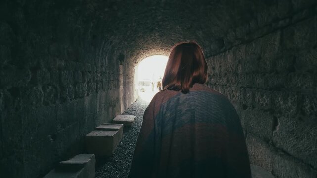 Young Woman Walks Through a Tunnel with Light at the End