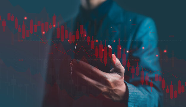 Businessman using smartphone with red falling stock market graph and candlestick chart symbolizing financial crisis, investment loss, trading risk, and economic downturn concept in finance background.