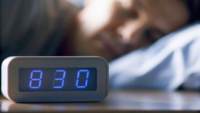 A person sleeping next to a digital alarm clock displaying 8:30, capturing a moment of rest and tranquility.