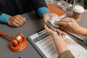 A businesswoman is handing over cash to a lawyer in an office, representing corruption, bribery, or...