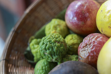 Closeup of fresh tropical fruit like bergamot, kaffir lime, and passion fruit in natural woven basket. vibrant and organic selection offers healthy, tasty ingredient