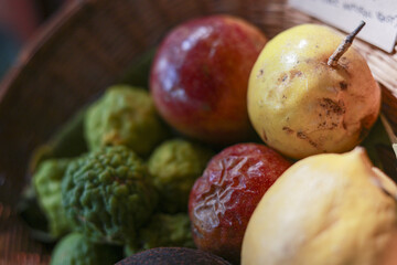 Close up of fresh tropical passion fruit and kaffir lime in basket. vibrant, organic fruit selection evokes healthy, natural, and exotic feeling from local market