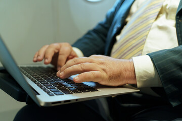 Businessman working on laptop in airplane business class during flight