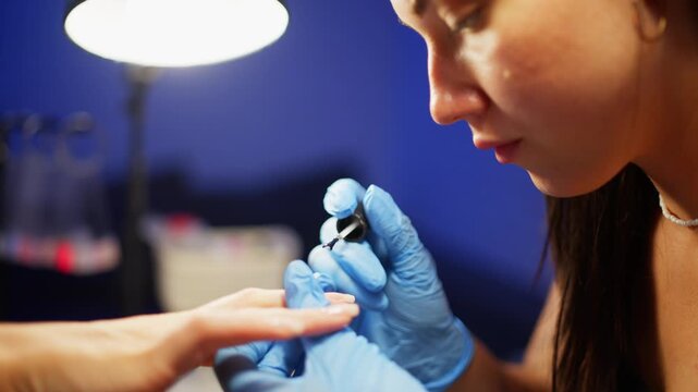 Close up of beauty master coating woman nails with gel polish in manicure studio demonstrating accurate work clean design and shiny finish for perfect professional nail care. High quality 4k footage