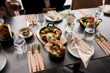 Elegant restaurant table setting with gourmet dishes, fresh bread, and appetizers served on modern tableware with gold cutlery in natural light – fine dining experience concept
