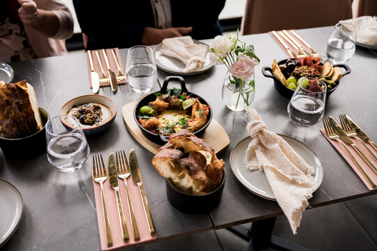 Elegant restaurant table setting with gourmet dishes, fresh bread, and appetizers served on modern tableware with gold cutlery in natural light &ndash; fine dining experience concept
