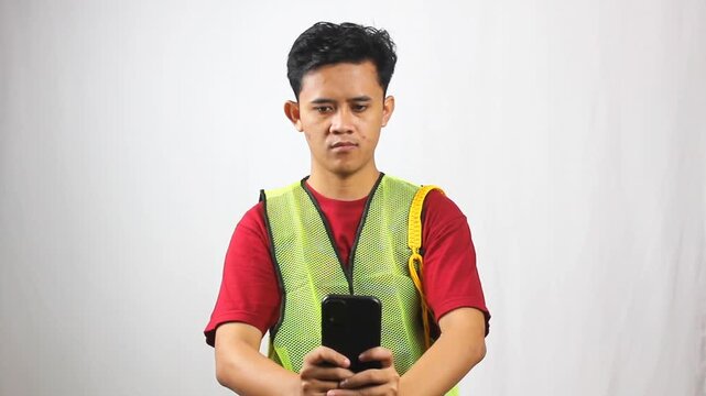 Parking attendant wearing green vest takes photo of illegal parking violation and reports it via mobile app on smartphone isolated on white background