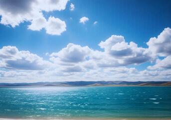 Obraz premium Qinghai lake water stretches toward a distant horizon under a vast sky filled with fluffy white clouds, showcasing the expansive natural beauty of Qinghai China.