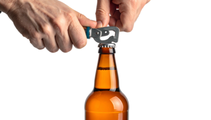 Close-up shows hands opening a brown bottle with a bottle opener against a dark background