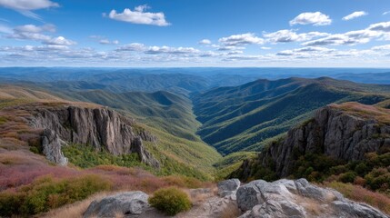 Vast Mountain Valley With Jagged Rocks And Colorful Autumn Foliage Under A Blue Sky With White Clouds