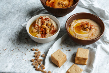 Three bowls of delicious hummus topped with spices and oil
