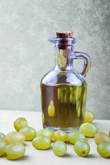 Glass bottle of olive oil surrounded by fresh green grapes