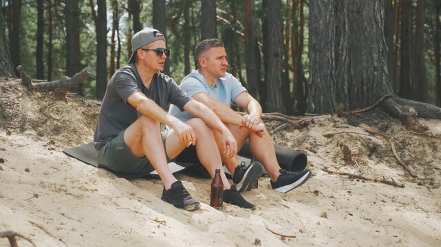 Men outdoors enjoying, Friends sharing drinks outside happily, Men relaxing and drinking outdoors on gentle slope, Groups of men and friends happily relaxing with drinks on scenic hillside outdoors