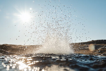 A powerful geyser explosion sending water droplets shimmering in the sunlight