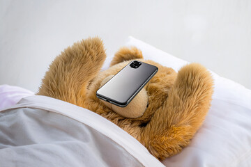 ベッドで寝落ちしてスマホを顔に落とすテディベア