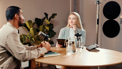 Podcast, microphone and people in studio for talk show, radio or live streaming with tablet. Podcaster, recording audio and host with guest for interview question, content creation and broadcast