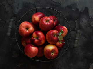 Ripe red autumn apples in a metal basket on the dark background