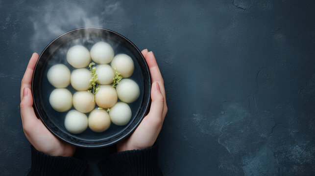 Hands holding steaming bowl of tangyuan glutinous rice balls for Dongzhi Festival winter solstice celebration