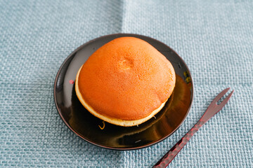 黒皿にのせたどら焼きを青マット背景で撮影