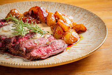 Tender sliced steak and roasted potatoes gleam on a plate, garnished with rosemary