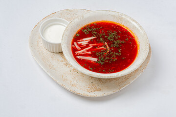 A bowl of vibrant red soup is presented alongside fresh sour cream, ready to be enjoyed