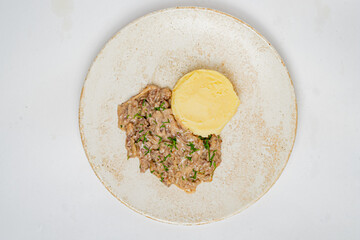 Beef stroganoff and mashed potatoes served on a round plate, ready to enjoy